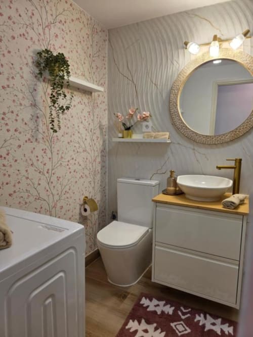 Baño moderno en villa Auramar de Smart Rent Fuerteventura con accesorios blancos, detalles dorados, papel tapiz floral y formas redondas