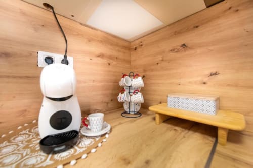 Interior de cabaña de madera en villa Auramar con cafetera, tazas en repisa y banco de comedor en Fuerteventura