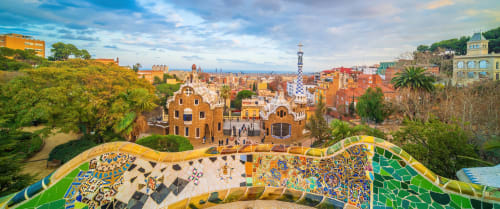 Terraza de mosaicos coloridos del Parque Güell con vistas al vibrante paisaje urbano y la arquitectura de Barcelona