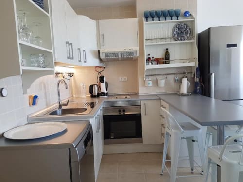 Cocina moderna en el apartamento Casa Storm de Smart Rent Fuerteventura, España, con muebles blancos y electrodomésticos de acero inoxidable,