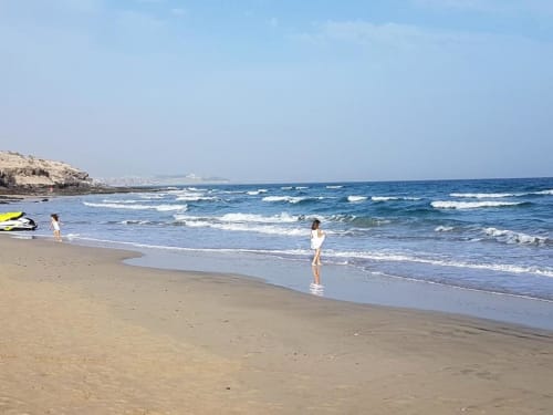 Huéspedes disfrutando de la playa arenosa con olas del océano en el apartamento Casa Storm de Smart Rent Fuerteventura con vistas al mar
