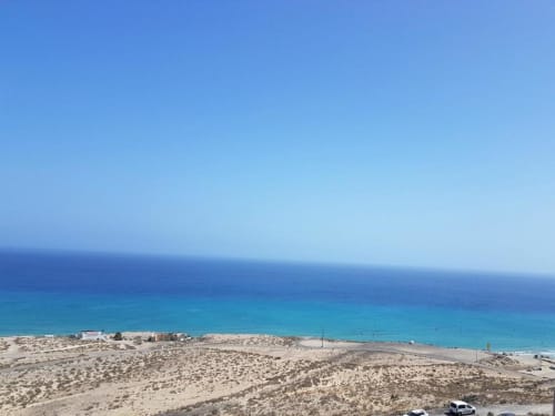 Vista del océano turquesa desde el apartamento Casa Storm en Fuerteventura con playa de arena y cielo azul despejado