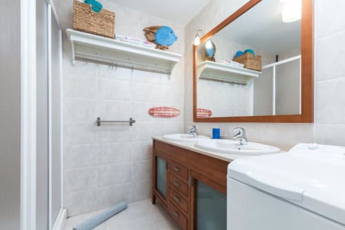 Baño moderno en apartamento Casa Storm de Smart Rent Fuerteventura con doble lavabo, tocador de madera y ducha abierta.