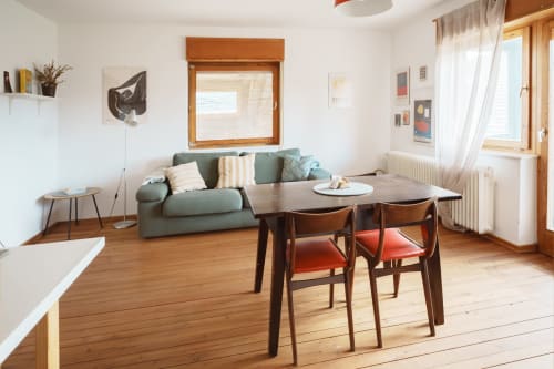 Bright apartment living room with green sofa, dining table, wooden floors, and mountain views at Kmetija Pečnik, Prevalje