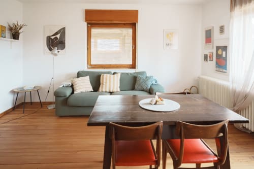 Modern living room with green sofa, wooden dining table, and red chairs at Kmetija Pečnik apartment in Prevalje