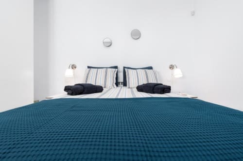 Dormitorio moderno en apartamento Smart Rent Fuerteventura con almohadas rayas, mantas oscuras y colcha turquesa