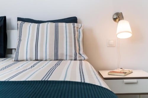 Ropa de cama rayada y aplique de pared en apartamento de Sunset Beach Tarajalejo en Smart Rent Fuerteventura