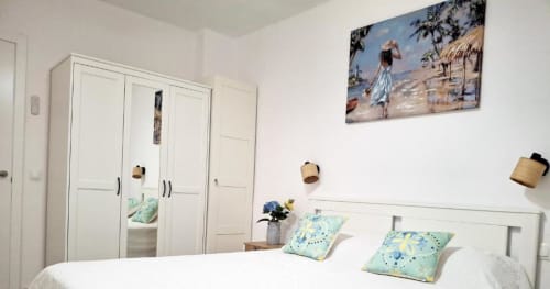 Luminoso dormitorio en el apartamento Alex's House de Smart Rent Fuerteventura con armario blanco, almohadas azules estampadas y