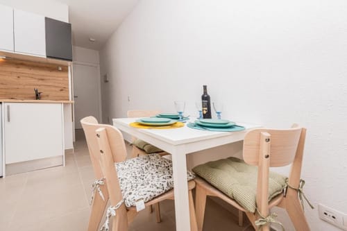 Moderna cocina-comedor en el apartamento Alex's House de Fuerteventura con mesa blanca, sillas de madera y totalmente equipada