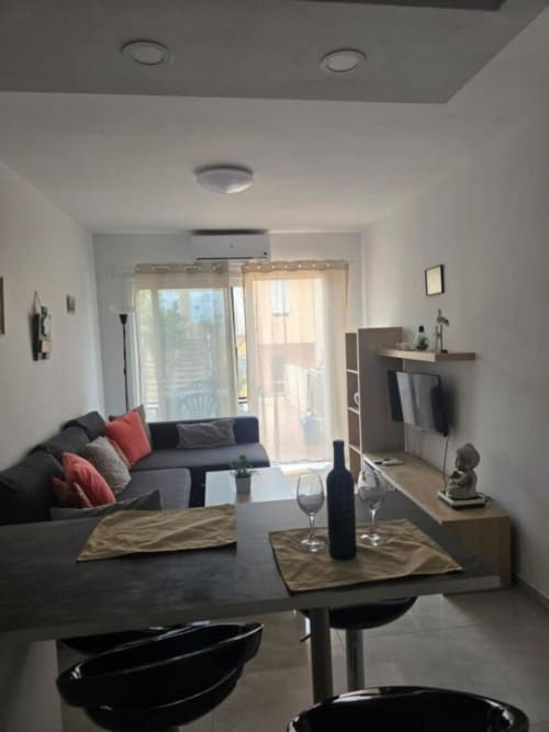 Moderno salón con sofá, comedor, cocina, acceso a terraza y vistas al jardín en Smart Rent Fuerteventura