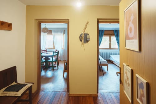Bright hallway in Borovc Pine Suite at Kmetija Pečnik with hardwood floors, yellow walls, and doorways to dining and bedroom