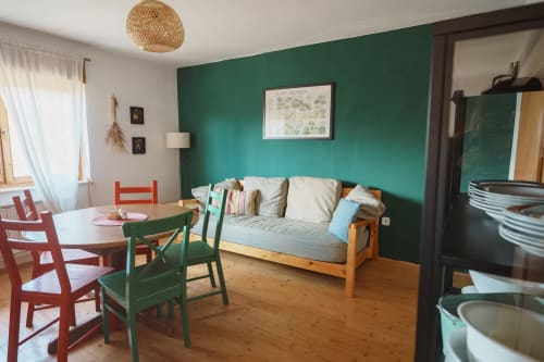 Borovc apartment at Kmetija Pečnik with green accent wall, wooden sofa, dining area, and mountain views in Prevalje, Slovenia
