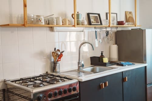 Modern kitchen in Borovc Pine Suite at Kmetija Pečnik with gas stove, sink, wooden shelves and white tile backsplash