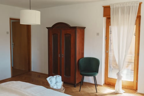 Borovc apartment bedroom at Kmetija Pečnik with wooden wardrobe, green chair, hardwood floors, and mountain view access