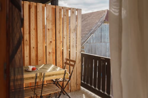 Sunny terrace at Kmetija Pečnik with wooden privacy screen, dining table, and mountain views near Prevalje, Slovenia
