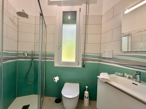 Bagno moderno al Welcome Varigotti con piastrelle verdi, box doccia, wc e lavabo a Finale Ligure, Italia