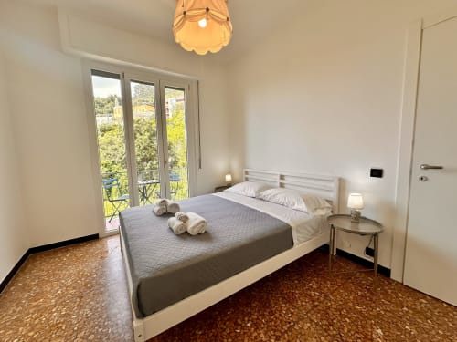 Camera luminosa al Welcome Varigotti con balcone vista mare, letto bianco, pavimento in sughero e luce naturale a Varigotti