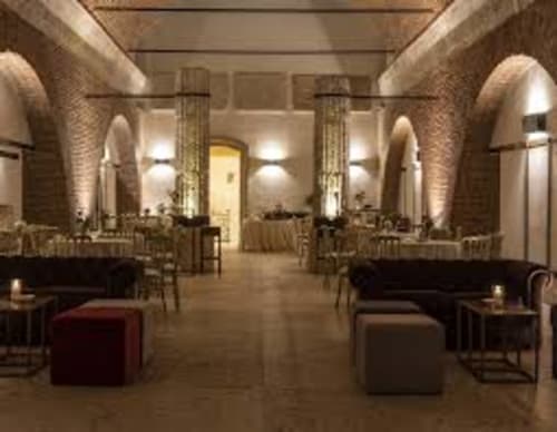 Elegante zona lounge con soffitti in mattoni ad arco, sedute bordeaux e colonne nell'hotel di Verona