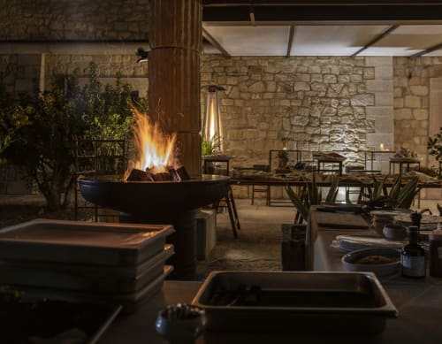Elegante cortile esterno di STAYIN Verona con fuoco, muri in pietra e area dining al tramonto
