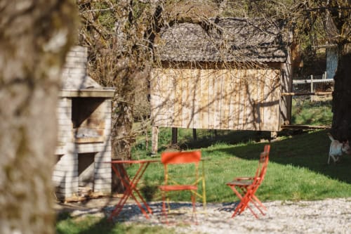 Red chairs in garden courtyard at Kmetija Pečnik farmhouse B&B in Prevalje, Slovenia