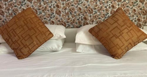 Cama de Casa Gallinera con almohadas blancas y cojines texturados marrones contra cabecero floral, Benissivà