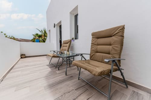 Patio moderno del apartamento Casa Andre en Fuerteventura con sillas tapizadas en beige, mesita y paredes blancas