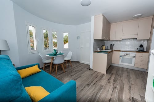 Estudio moderno y diáfano en Casa Andre, Fuerteventura con sofá turquesa, cocina equipada, comedor y vistas al océano