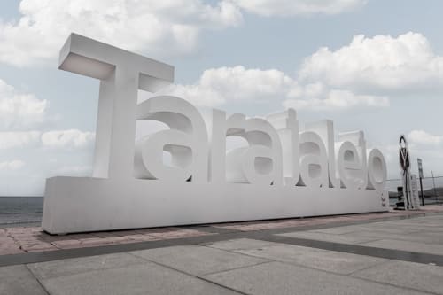 Letrero de paseo marítimo de Tarajalejo en Fuerteventura, España, con letras blancas sobre cielo nublado y océano de fondo