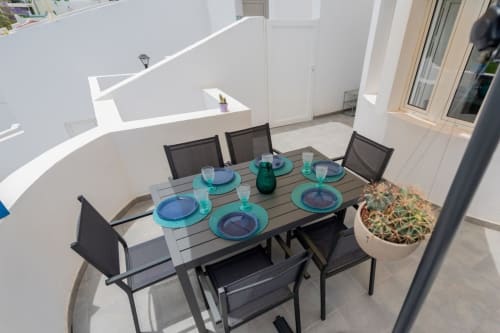 Zona de comedor en terraza exterior de Casa Andre, Smart Rent Fuerteventura, con mesa preparada para cuatro personas y cactus en maceta