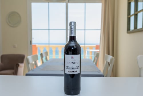Botella de vino Fidencio Crianza sobre la mesa en apartamento de Smart Rent Fuerteventura con terraza con vistas al océano de fondo