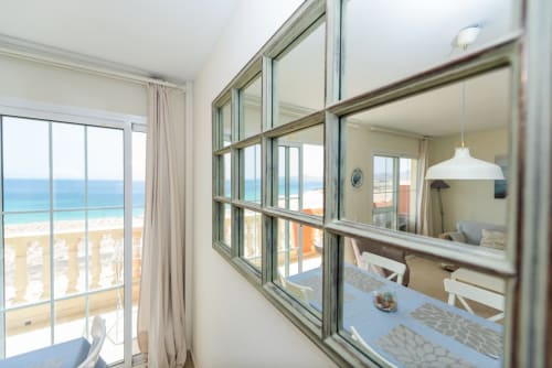 Luminoso apartamento frente al mar con vistas al océano, ventanales modernos, comedor y lámpara colgante blanca