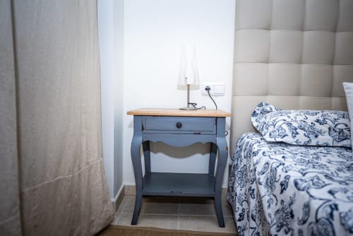 Dormitorio en Smart Rent Fuerteventura con mesita azul, ropa de cama blanca, cabecero acolchado y lámpara de escritorio