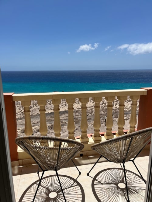 Balcón frente al mar con sillas de mimbre con vista al mar turquesa en Casa de los Amigos, Fuerteventura