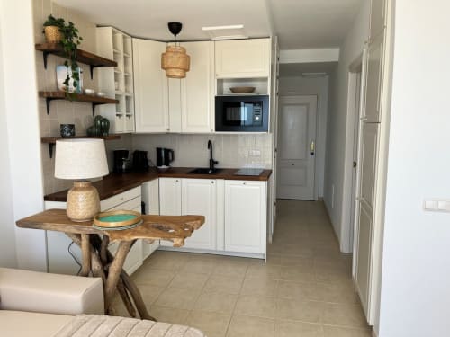 Moderno apartamento con cocina en Smart Rent Fuerteventura, muebles color crema, mesa de madera y planta abierta