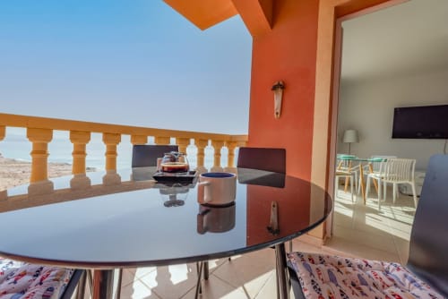 Terraza con mesa redonda, vistas al mar y detalles arquitectónicos naranjas en el apartamento Casa Sky de Smart Rent Fuerteventura