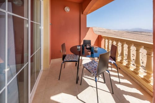 Balcón soleado con mesa de comedor y sillas con vistas al campo de Fuerteventura en Casa Sky
