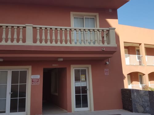Exterior del apartamento Smart Rent Fuerteventura Casa Sky con fachada roja, balcón y entrada a terraza en día soleado