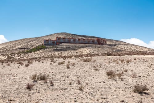 Edificio del hotel Smart Rent Fuerteventura en ladera rocosa con paisaje desértico bajo cielo azul despejado