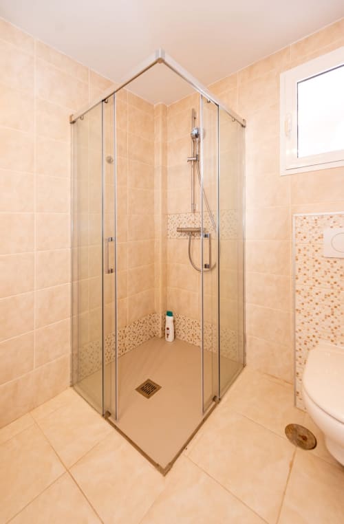 Moderno lavabo de esquina con cristal en el apartamento Casa Sky de Smart Rent Fuerteventura con azulejos beige y ducha de lluvia
