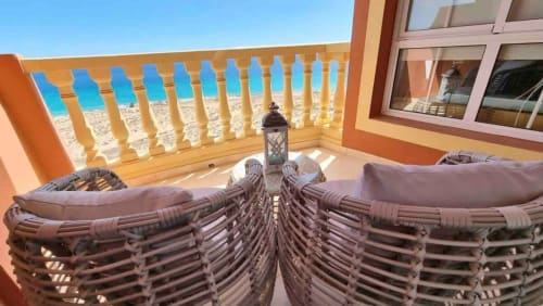 Balcón frente al mar con tumbonas tejidas, vistas al océano y barandillas de madera en Casa Kiteloop, Fuerteventura