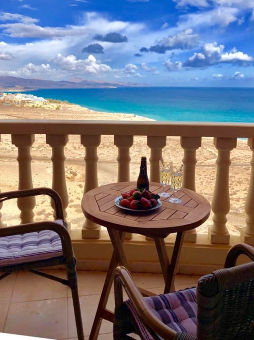 Balcón frente al mar en Smart Rent Fuerteventura con vistas al mar turquesa, bebidas y fruta fresca