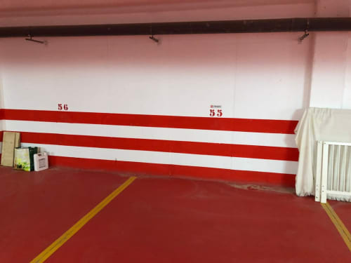 Espacio de aparcamiento 55 en Smart Rent Fuerteventura con marcas de pared roja y blanca y línea amarilla en el suelo