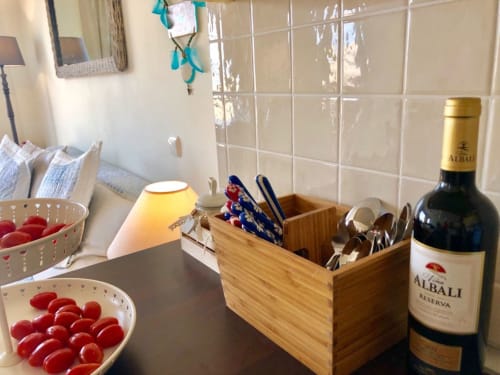 Encimera de la cocina del apartamento Elisabeth en Smart Rent Fuerteventura con vino, utensilios, tomates frescos y amenidades