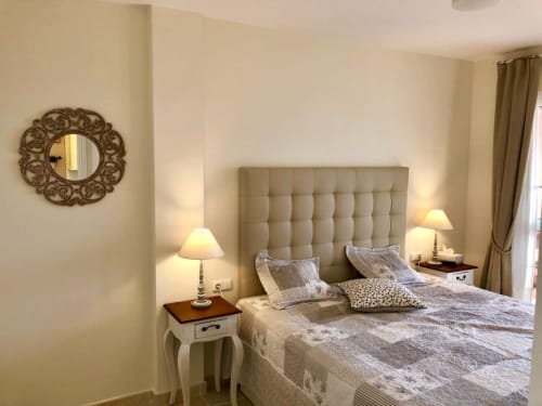 Habitación elegante en Smart Rent Fuerteventura con cabecero tapizado beis, camas individuales, lámparas de noche y espejo ornamental