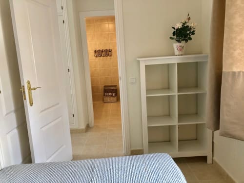 Dormitorio moderno en apartamento Elisabeth de Smart Rent Fuerteventura con estanterías blancas, cama a rayas y puertas de entrada