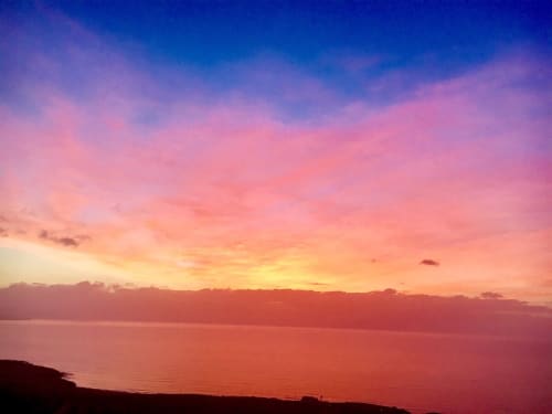 Atardecer espectacular sobre el océano en Smart Rent Fuerteventura, con cielo rosa y naranja reflejándose en aguas tranquilas