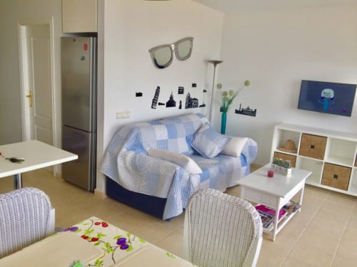 Moderno estudio en Smart Rent Fuerteventura con cama, kitchenette, TV y decoración temática de playa