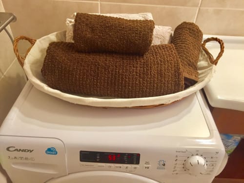 Toallas marrones en cesta blanca sobre lavadora en apartamento Smart Rent Fuerteventura