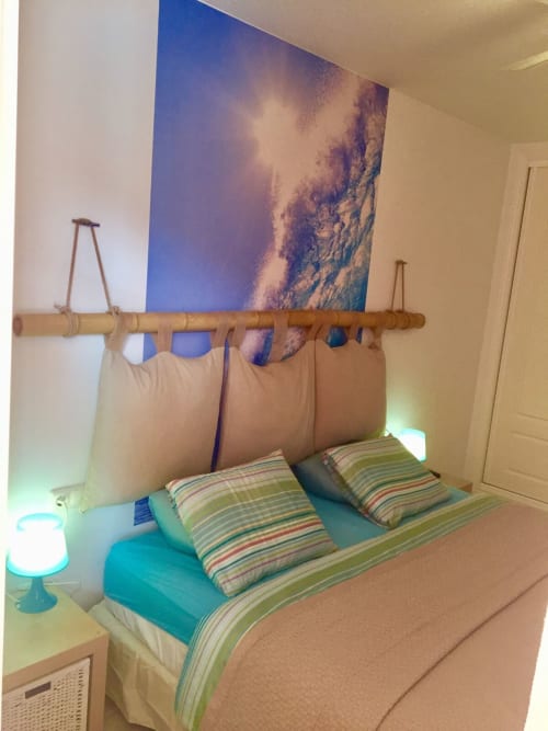 Dormitorio acogedor en Smart Rent Fuerteventura con ropa de cama a rayas, cabecero de bambú, detalles turquesas y arte temático playero