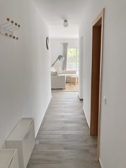 Moderno pasillo del apartamento Smart Rent Fuerteventura con suelo de madera, que conduce a la acogedora sala amueblada con vistas al océano